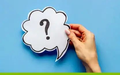 A hand holding a paper speech bubble cutout with a black question mark on a blue background.