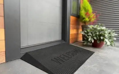 Black rubber door threshold ramp with “WELCOME” embossed on the surface, placed in front of a house entrance.